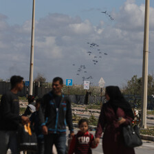 A group of people walk as parachuted packages are visible in the air behind them