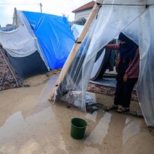 A woman stand ankle deep in brackish water in a tent