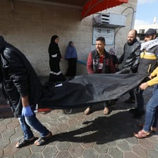 Men carry a dead body in a black shroud 