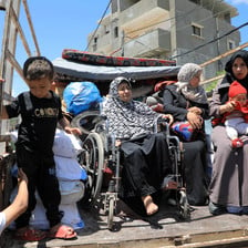 Women, one of them in a wheelchair, and children sitting in the back of a truck 