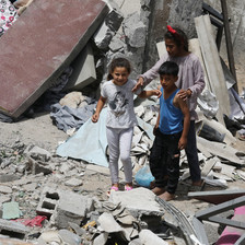 Three children amid what remains of a building destroyed by Israel 