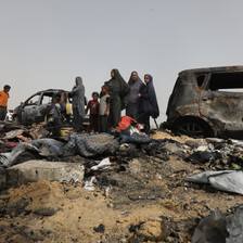 A number of people beside badly burned vehicles in southern Gaza 
