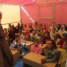 A teacher and children in a tent serving as a classroom 