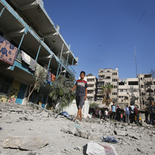 A boy walks beside a school which has been attacked by Israel 