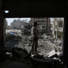 A man looks out from a damaged building at destruction around him in central Gaza 