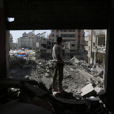 A man looks out from a damaged building at destruction around him in central Gaza