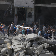 Men carry a dead body through what remains of a building attacked by Israel in central Gaza 