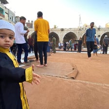 A boy stands with many adults behind him at the Grand Mosque of Gaza City 