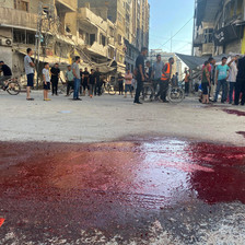 People stand near a large blood stain in Gaza City 