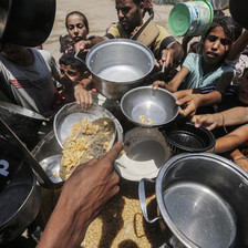 Children and at least one adult hold pots and other utensils as food aid is distributed in Gaza 