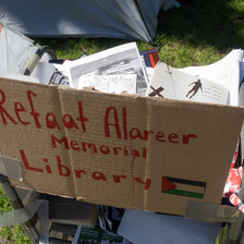 A cardboard sign reading Refaat Alareer Memorial Library 