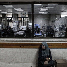 A woman sits below a window to a treatment room