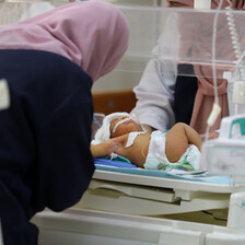 A woman leans over a baby