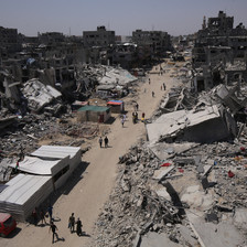 A bird's eye view of a dirt road with destroyed buildings and rubble on either side