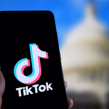 A TikTok logo is in front of a blurred image of the US Congress