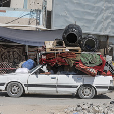 A white car weighed down with belongings strapped to its roof