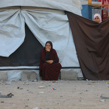 A woman sits in front of a makeshift tent