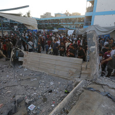 People gather in a hugely damaged school after it was attacked by Israel 