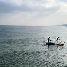 Two fishers at sea in a small boat