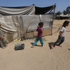 Displaced children walk beside a makeshift tent in Gaza 