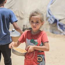 A child carries a bowl of food