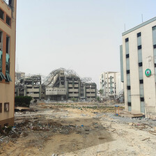 A view of bombed-out buildings and a dirt road in daylight