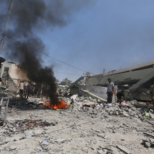 In the center of a scene of gray rubble is a red fire emitting black smoke