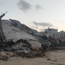 A collapsed house, its concrete roof sloping toward the ground