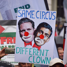 A sign with the faces of Keir Starmer and Rishi Sunak in clown make-up. Sign says: Same circus, different clown 