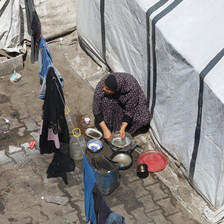 A view from above of a woman near a white tent, washing dishes.