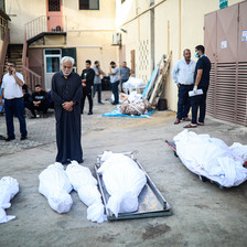 Men standing near shrouded bodies outside Al-Aqsa Martyrs Hospital in Deir al-Balah