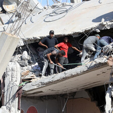 Men stand in the rubble of a building