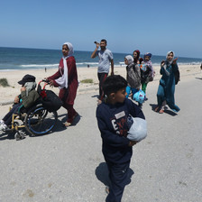 People wsalking along a sandy road carrying their belongings