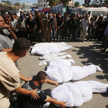 A group of mourners surround six corpses of various sizes wrapped in white shrouds