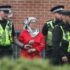 A woman in a Palestinian keffiyeh is arrested by British police