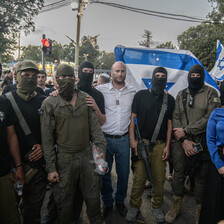 A group of masked and armed people pose with two Israeli legislators