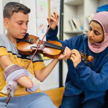 A one-handed boy practices violin with his teacher