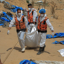 Three men in hazmat suits and face masks carry a wrapped body between them