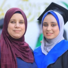 Two women, one in a graduation cap, smile for the camera.