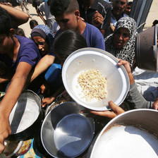 people crowd around a charity food distribution center for rice