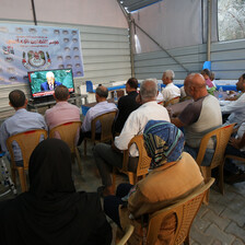 A group of people sit watching a monitor