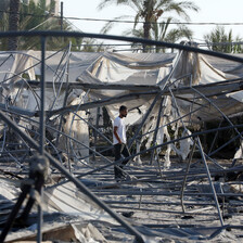 A man walks through the remains of burnt out tents