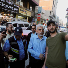 Yayha Sinwar surrounded by people in a street smiles for a selfie