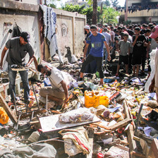 In daytime, men sift through the rubble and debris in the aftermath of an Israeli airstrike.