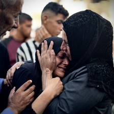 The head of crying young woman is held in the hands of another woman