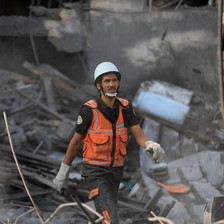 A man in hi vis vest walks through rubble