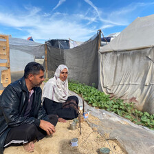 A man and a woman sits next to a strip of cultivated but sandy land