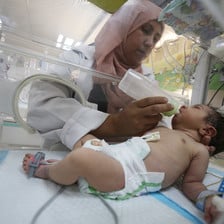 A baby is being fed milk inside an incubator