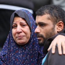 A woman in tears rests an arm around the shoulder of a young man