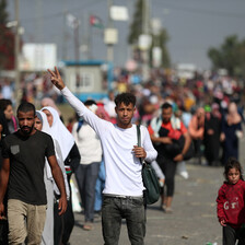 A young man in middle of street makes V for victory hand gesture